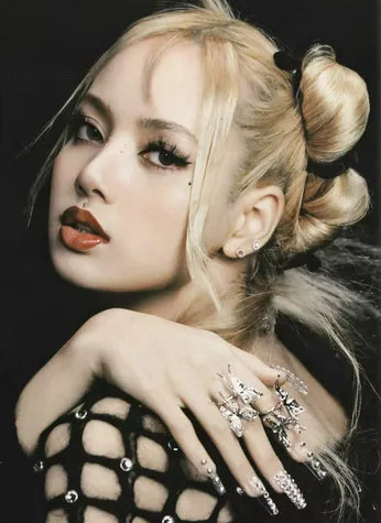 A portrait of a hand in jewelled rings and pavé nail pieces, raised to a blonde model’s shoulder.