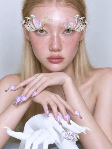 The model resting her chin on her hands, a Cobaea ring on every finger.