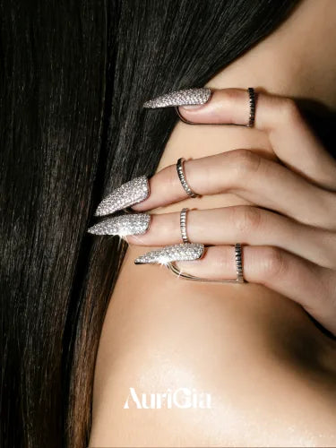 A hand resting on a bare shoulder against long dark hair, a Glint ring on each fingertip.
