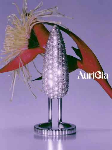 A crystal Pistil cluster on a polished stand against lilac, a red flower opening behind it.