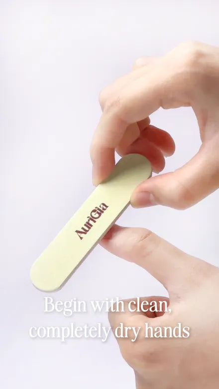 Step 1 of 10. Begin with clean, completely dry hands — a hand holding the AuriGia buffer from the kit.