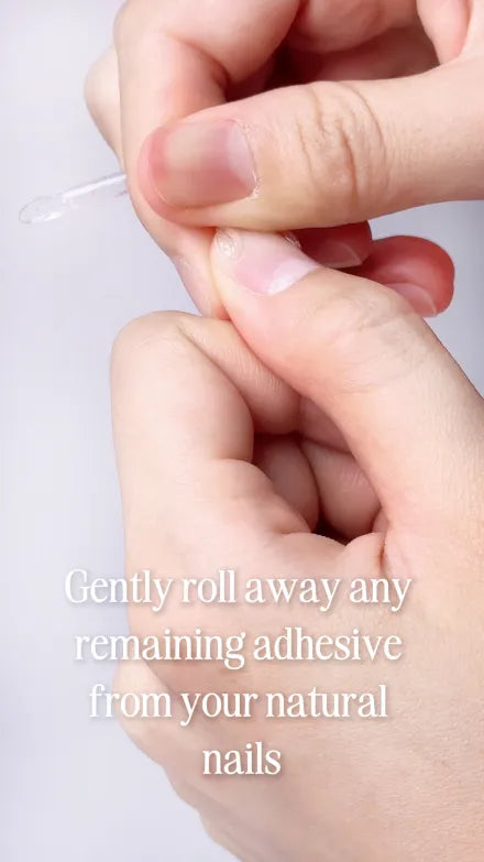 Step 3 of 10. Gently roll away any remaining adhesive from your natural nails — a clear sliver of old adhesive lifting off the nail.
